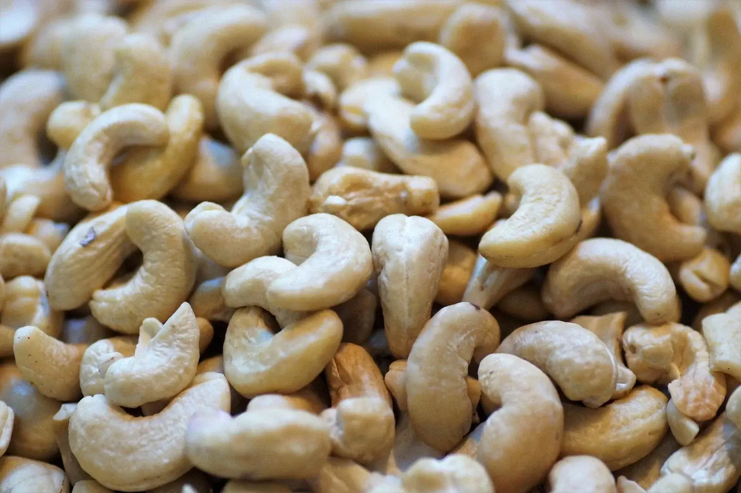 Cashew nuts with a creamy white appearance, shelled and ready for use, highlighting their curved, kidney-like shape and texture.